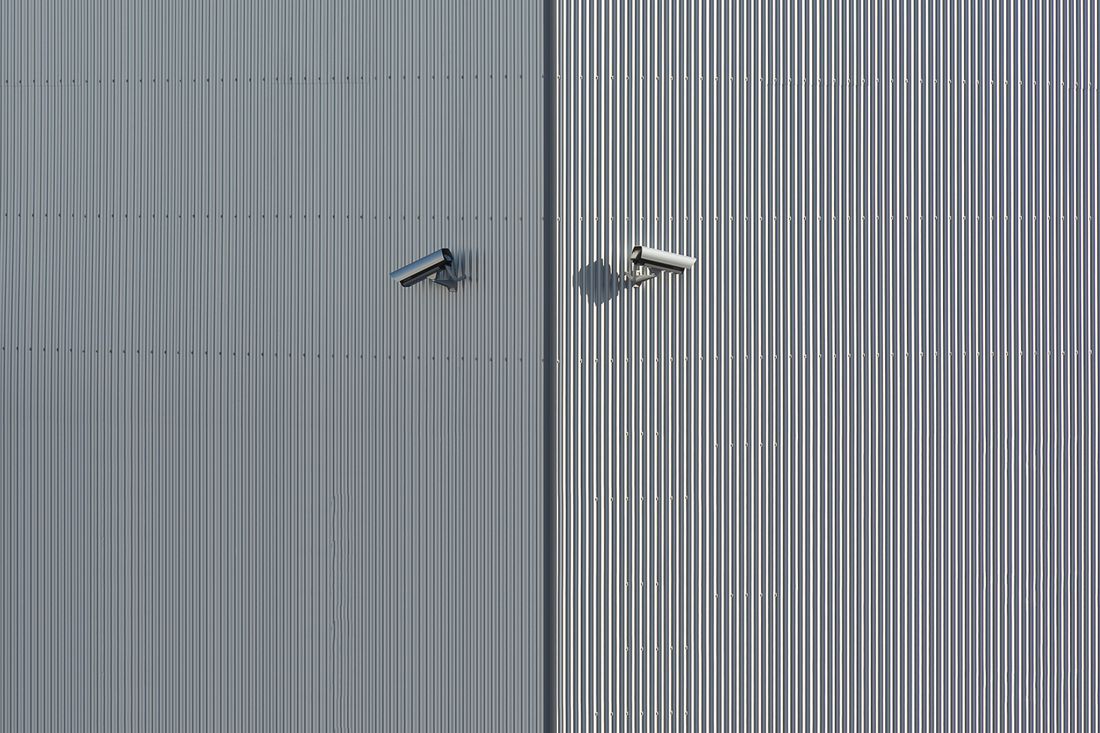 Two security cameras on a corrugated metal wall