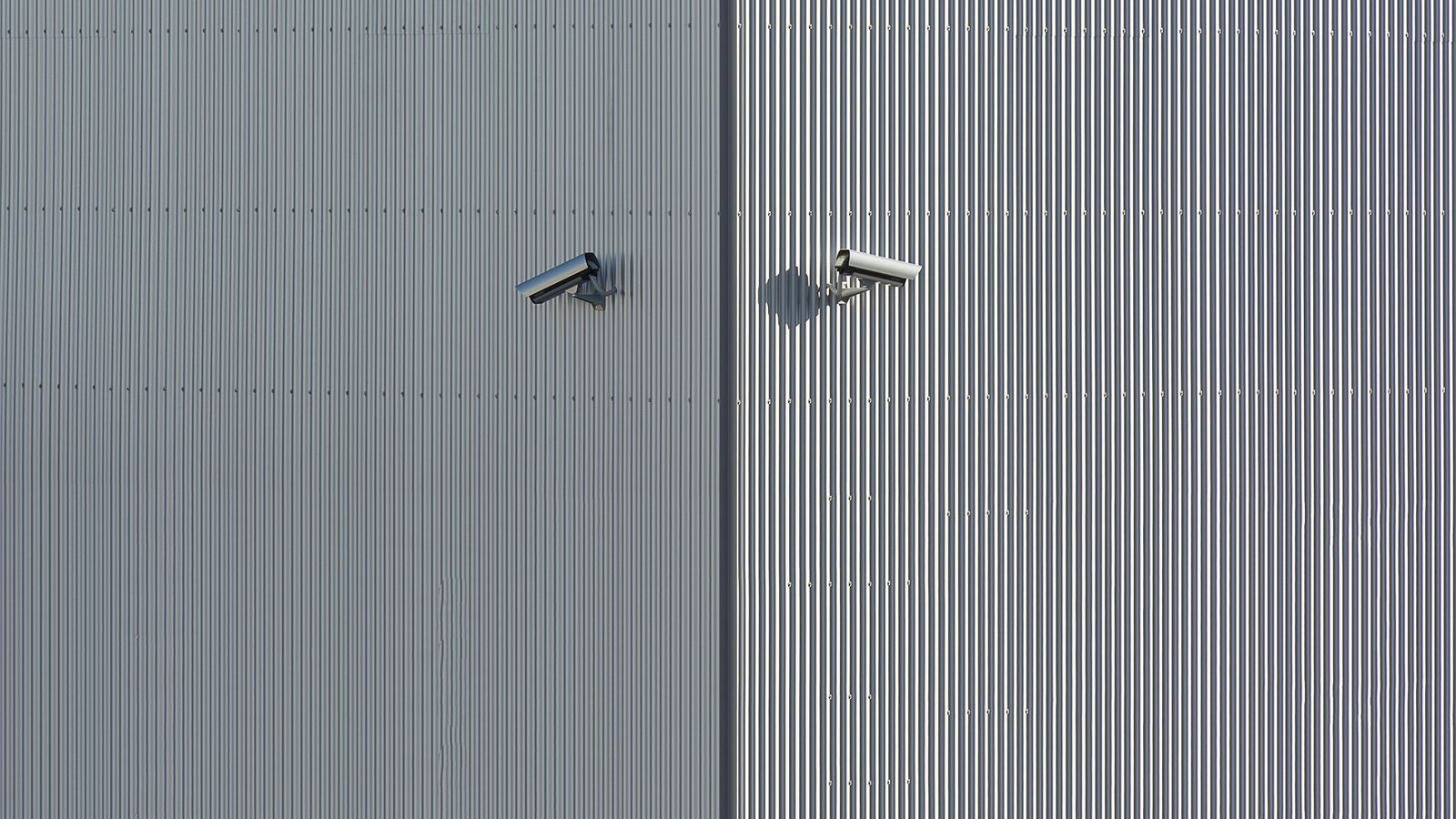 Corrugated metal wall with two mounted security cameras in a minimalist style.