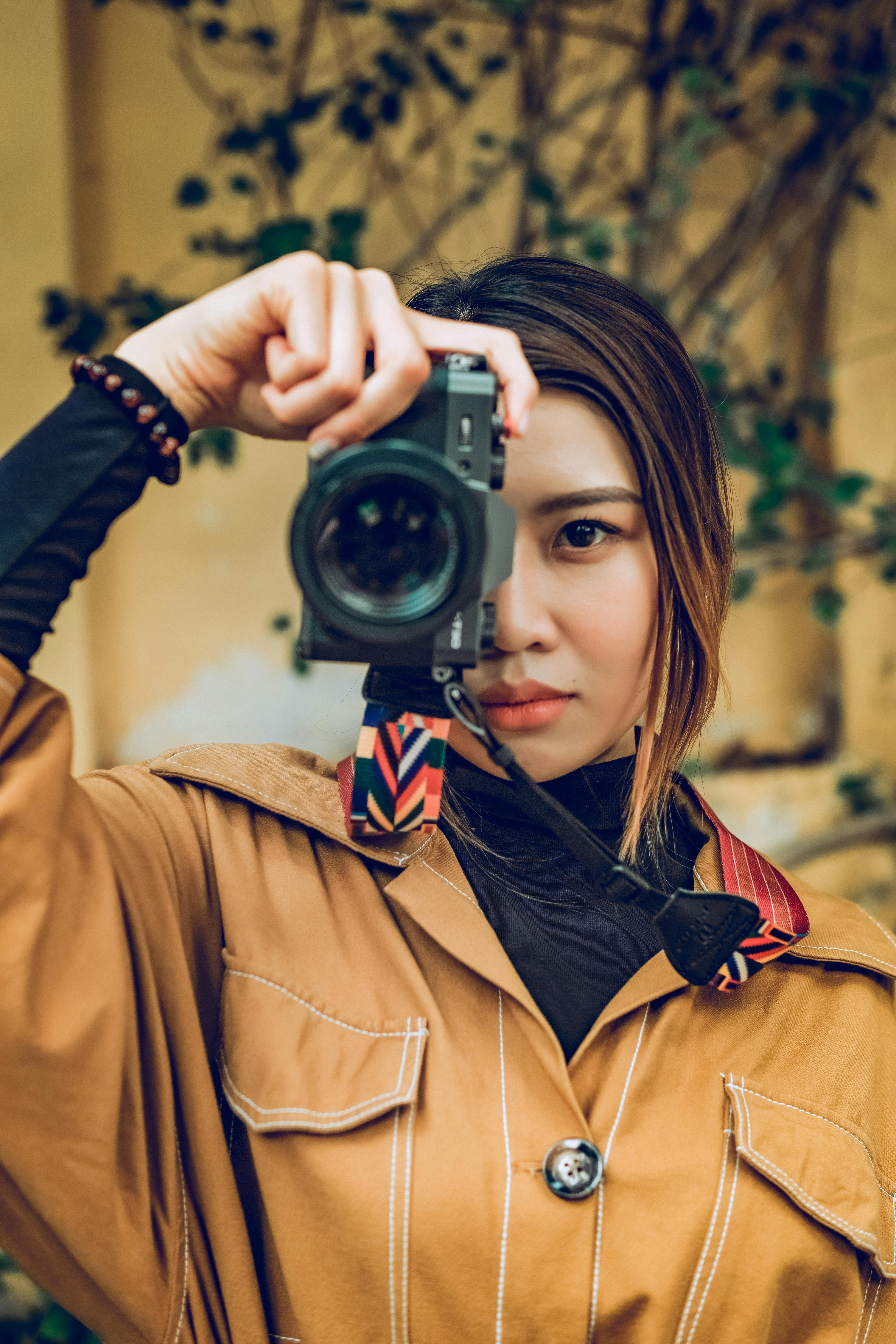 a woman in brown coat using camera