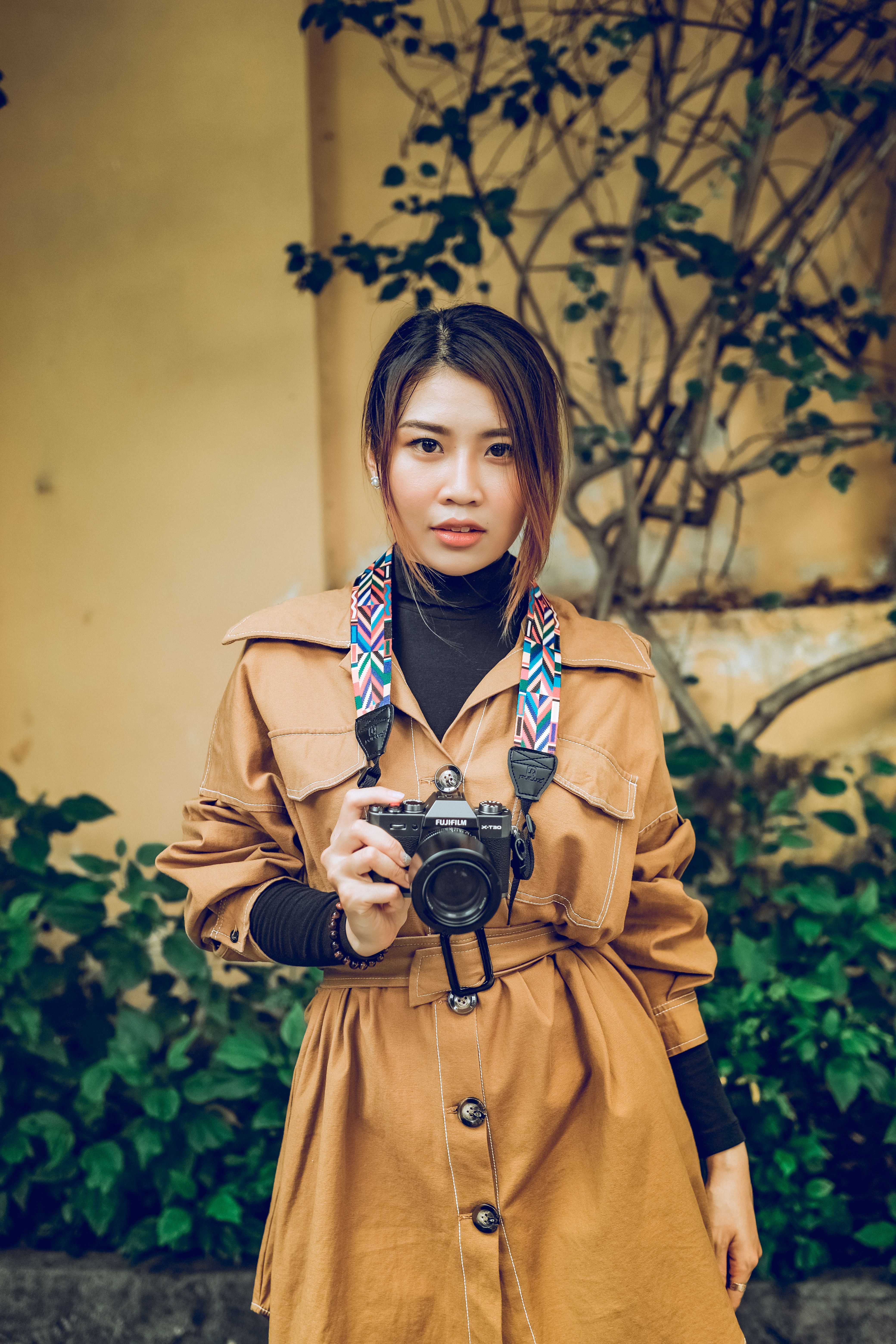 Photo of a Woman in a Brown Coat Holding a Camera · Free Stock Photo