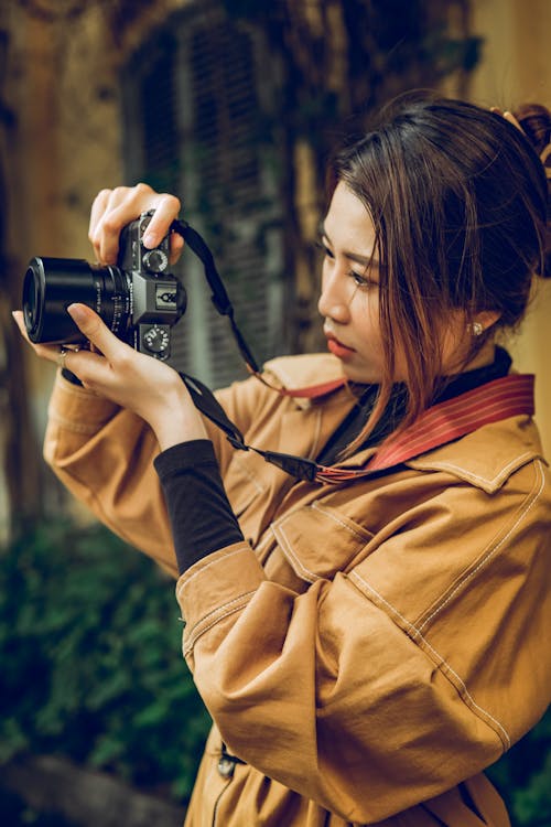 Woman in a Brown Coat Using a Black Camera