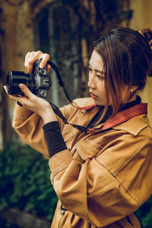 Woman in a Brown Coat Using a Black Camera · Free Stock Photo