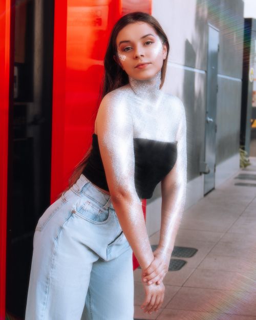 Free A glamorous portrait of a young woman in denim jeans and black top with glitter embellishments. Stock Photo