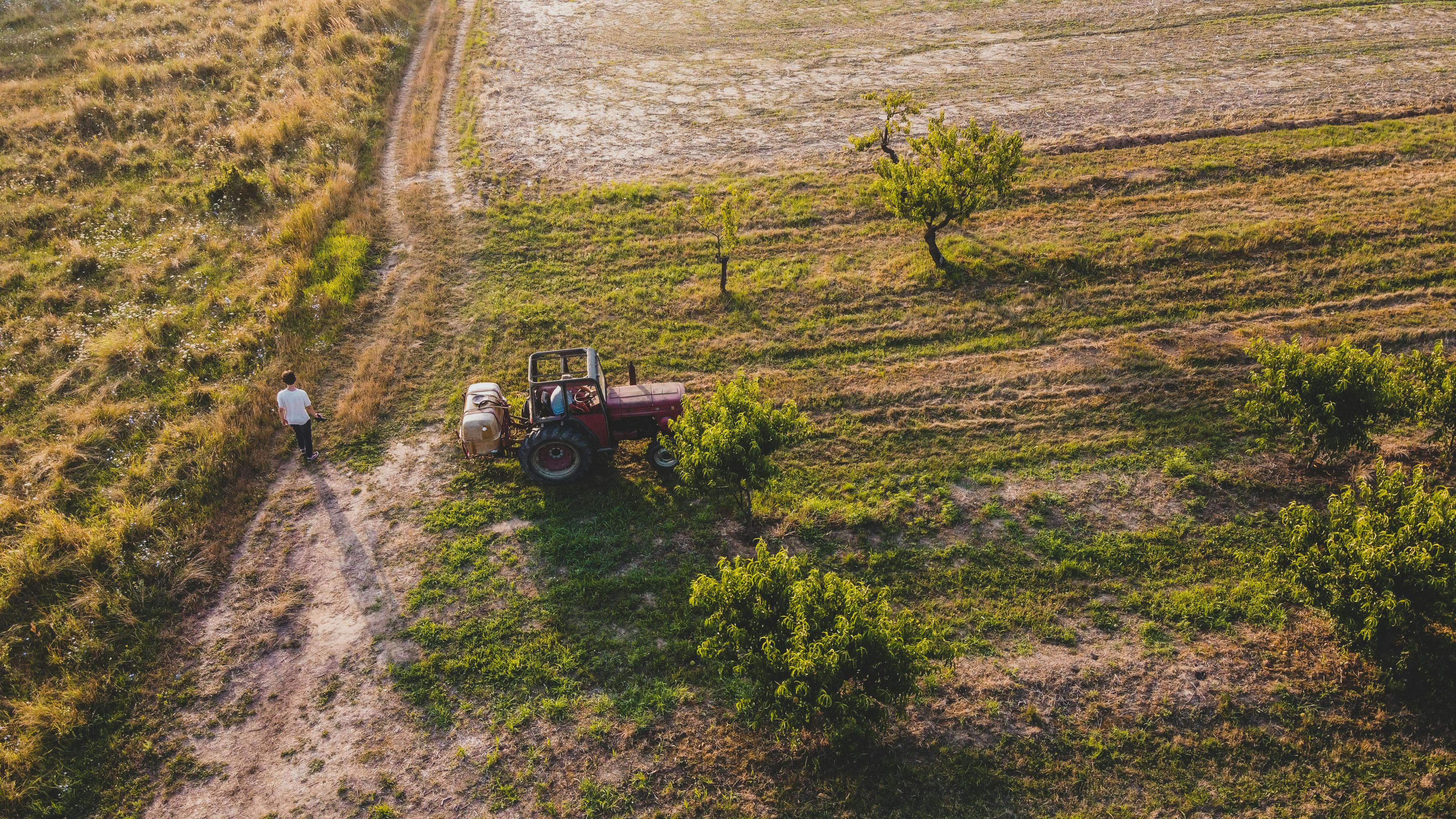 Drone shot of a tractor on a lush Romanian farm with surrounding greenery.