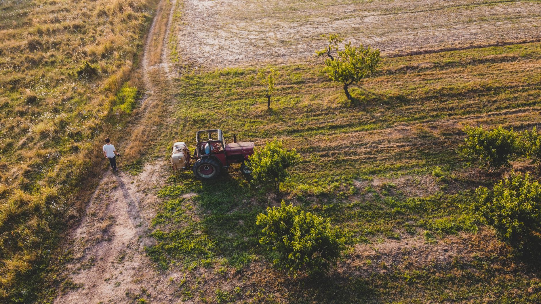 Drone shot of a tractor on a lush Romanian farm with surrounding greenery.