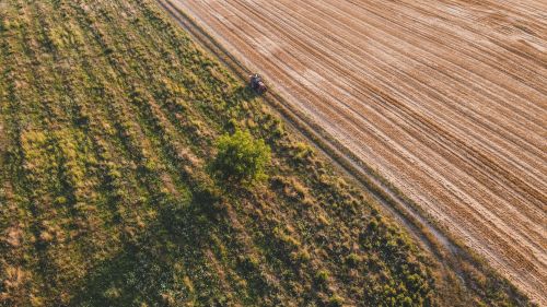 Free An aerial shot captures a tractor cultivating vast farmland during summer in Berlin, Germany. Stock Photo