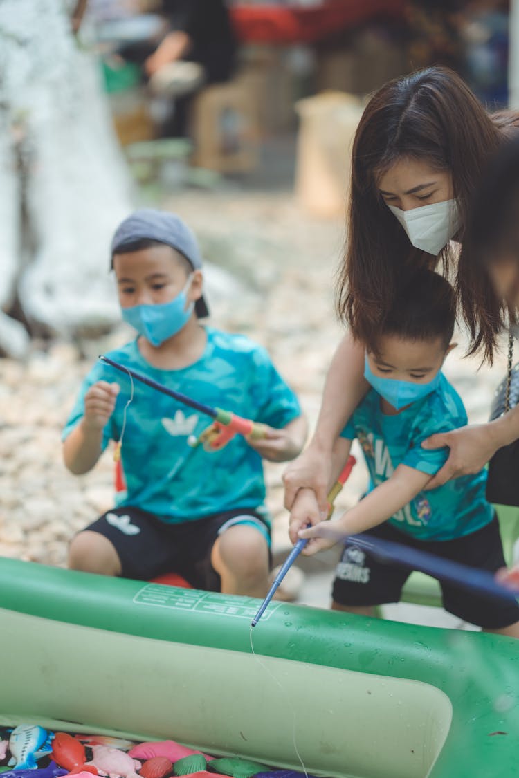 Woman Playing With Little Boys Outdoors