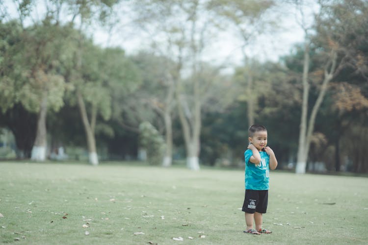 A Boy Standing On Green Grass