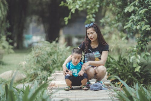 A Woman and a Boy Sitting on Wooden Walkway