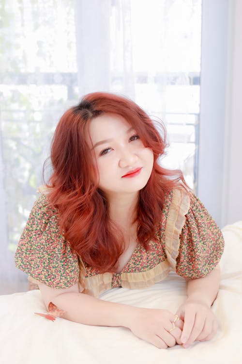 

A Woman in a Floral Dress Leaning on the Bed