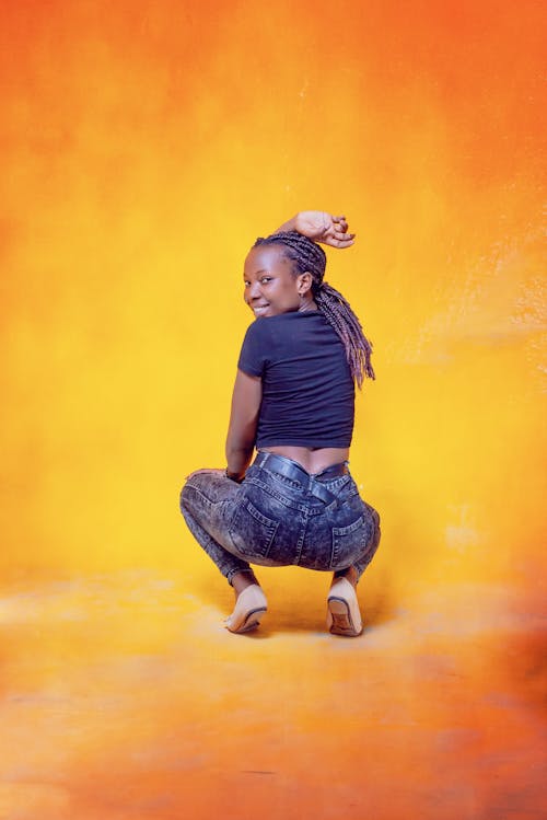
A Woman in a Black Shirt and Denim Pants Squatting