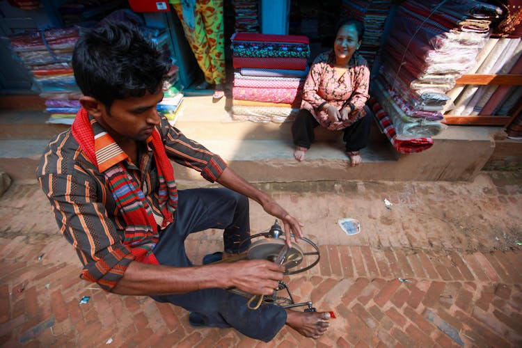 Man In Striped Shirt Sharpening A Tool