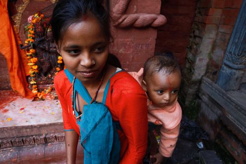 Free A South Asian woman carrying her baby in traditional attire at an ornate temple setting. Stock Photo