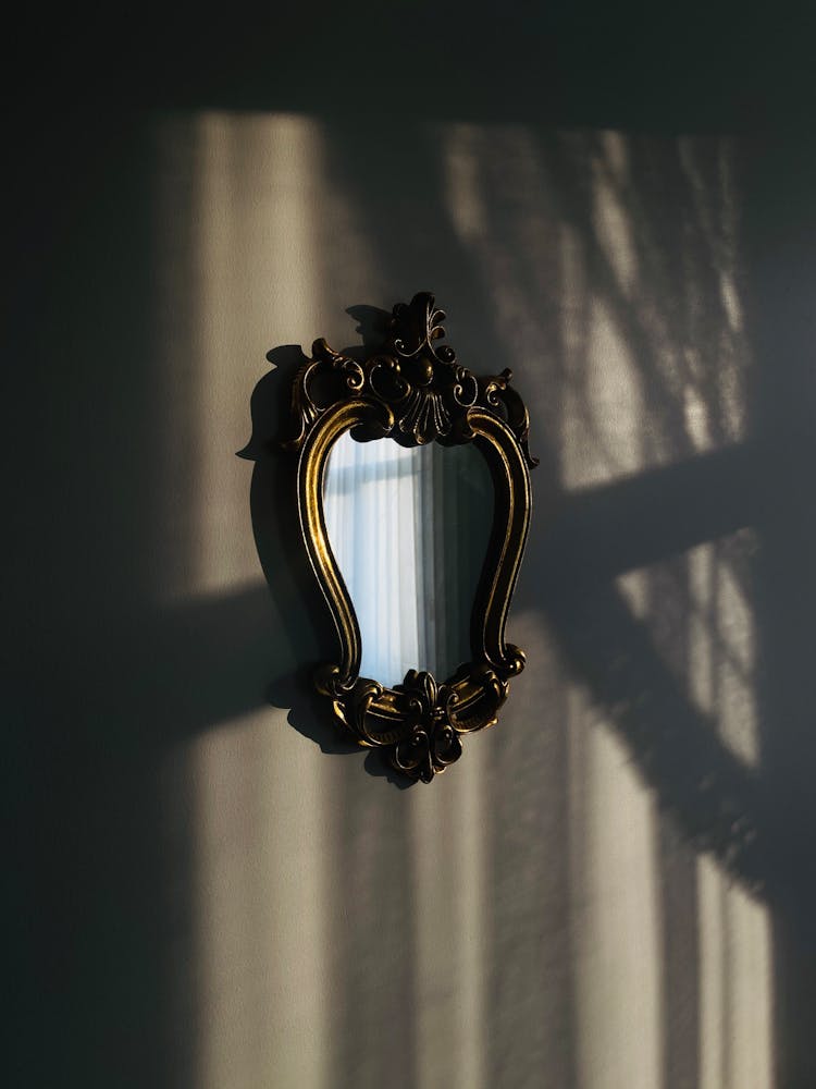 Wall Mirror With Intricate Gold Frame On A Concrete Wall