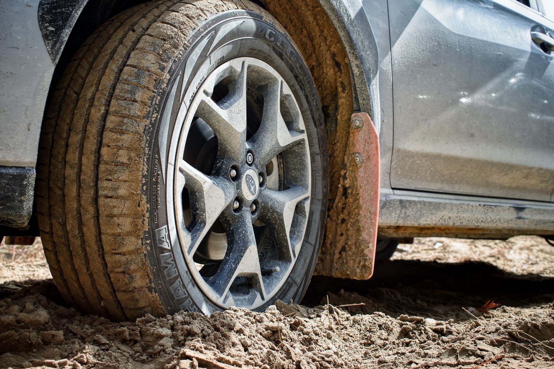 Close-up of a car tire on a muddy terrain, showcasing off-road adventure and vehicle resilience.