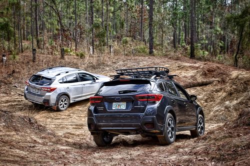 Free Two SUVs tackling a muddy offroad trail in a dense forest setting. Stock Photo