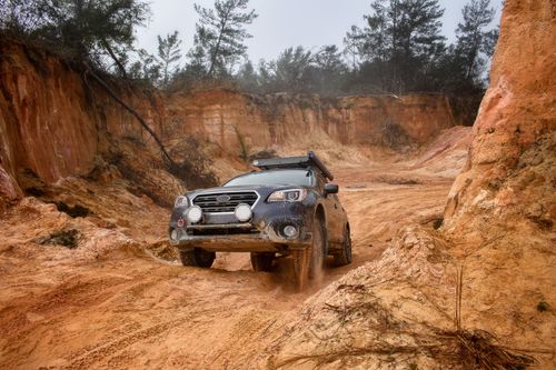 Free SUV navigating a challenging desert-like terrain with dusty tracks and rugged surroundings. Stock Photo