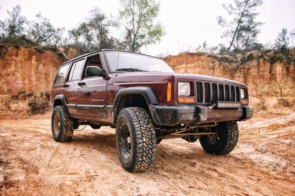 A rugged Jeep SUV navigating a muddy off-road track, showcasing durability and adventure.