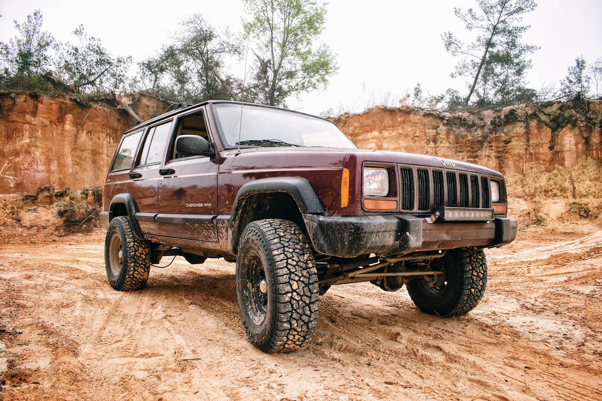 A rugged Jeep SUV navigating a muddy off-road track, showcasing durability and adventure.
