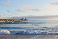 日落时分，宁静的景色中，木制码头延伸入海，海浪平静，天空柔和