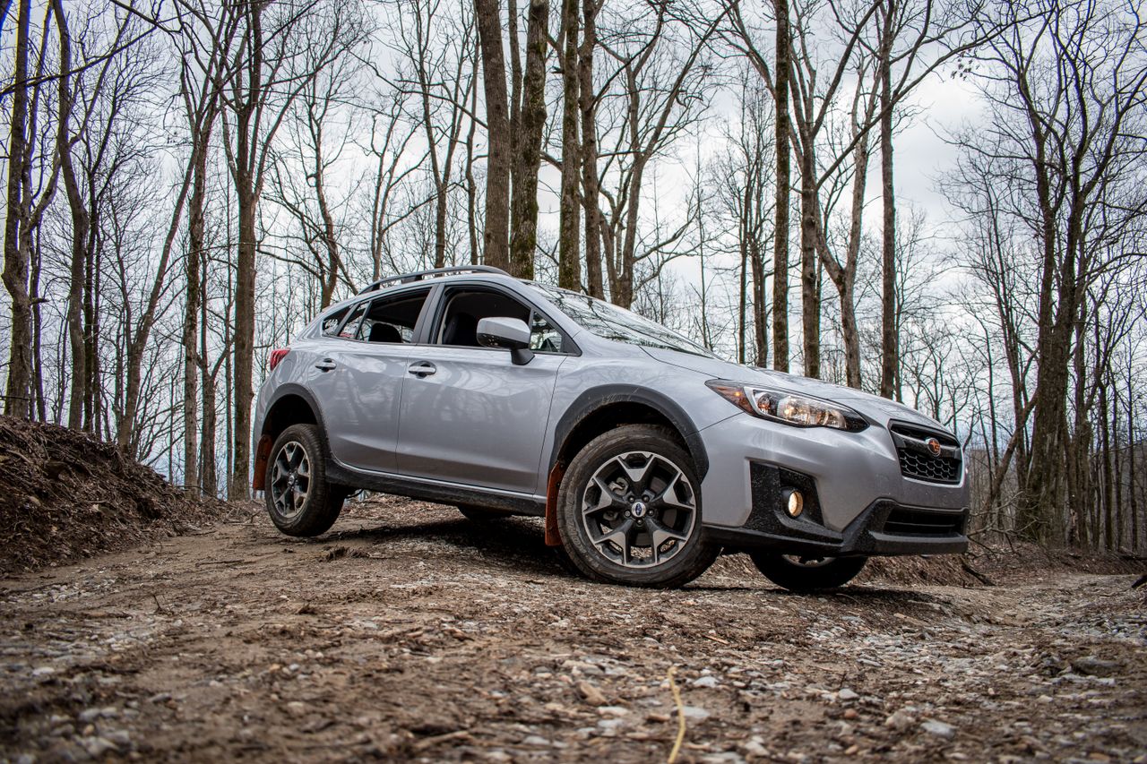 a silver suv car driving on a rocky dirt road through a forest showcas