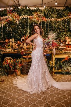Bride in a stunning lace wedding dress posing in a tropical indoor setting.