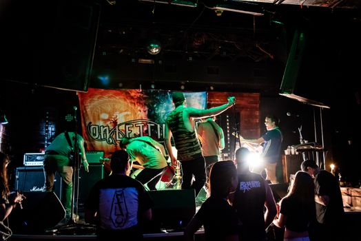 Energetic band performance on stage with vibrant lights and audience interaction.