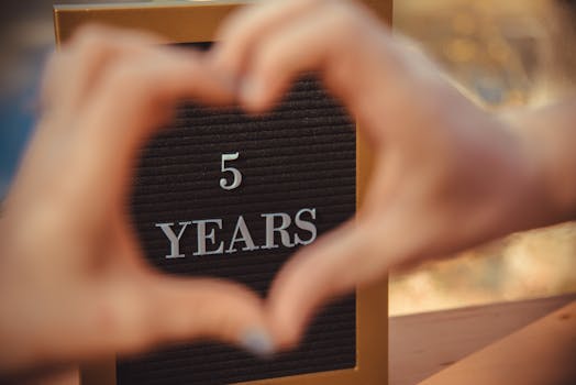 Celebratory sign for a 5-year anniversary framed by hands forming a heart.