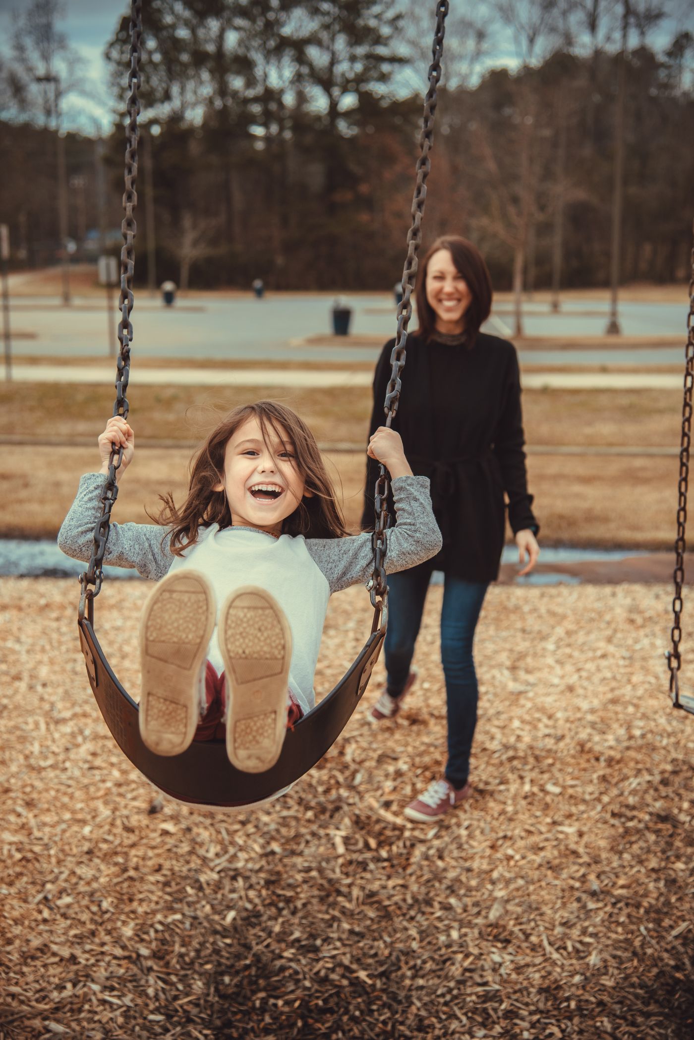 A child on a swing with their mother in a park