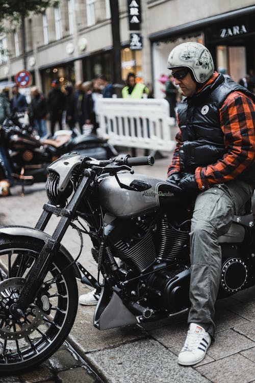 Man in Plaid Shirt and Black Vest Riding a Motorbike