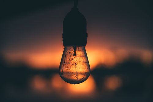 Free Silhouetted light bulb with sunset background creating a moody atmosphere. Stock Photo