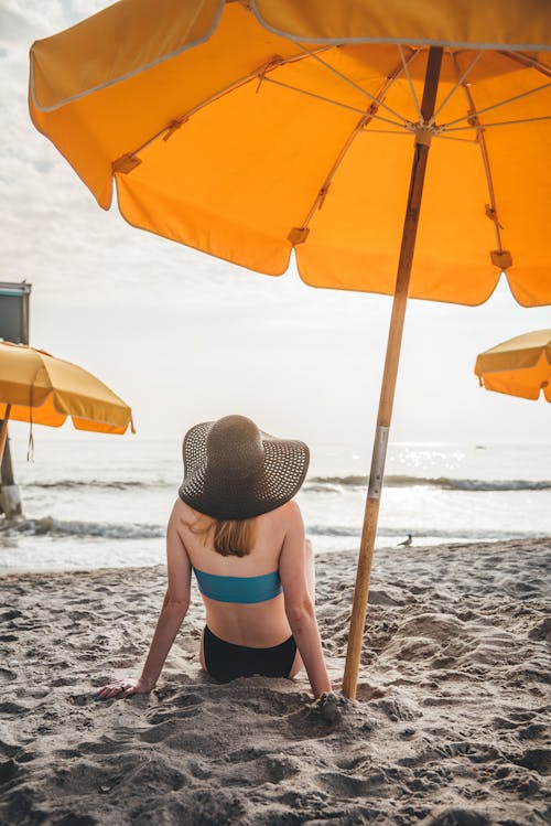 Woman Sitting on Beach with Umbrellas