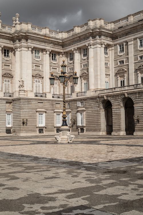 Free Elegant view of the Royal Palace of Madrid with ornate street light under a moody sky. Stock Photo