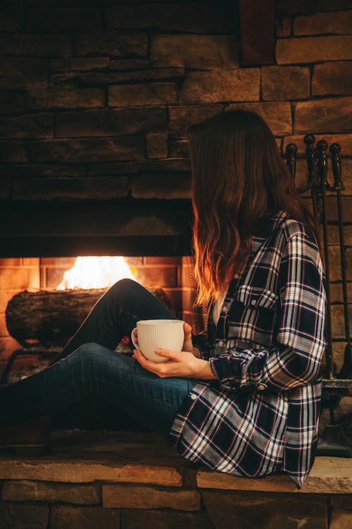 Free Woman Sitting Beside a Fireplace Stock Photo