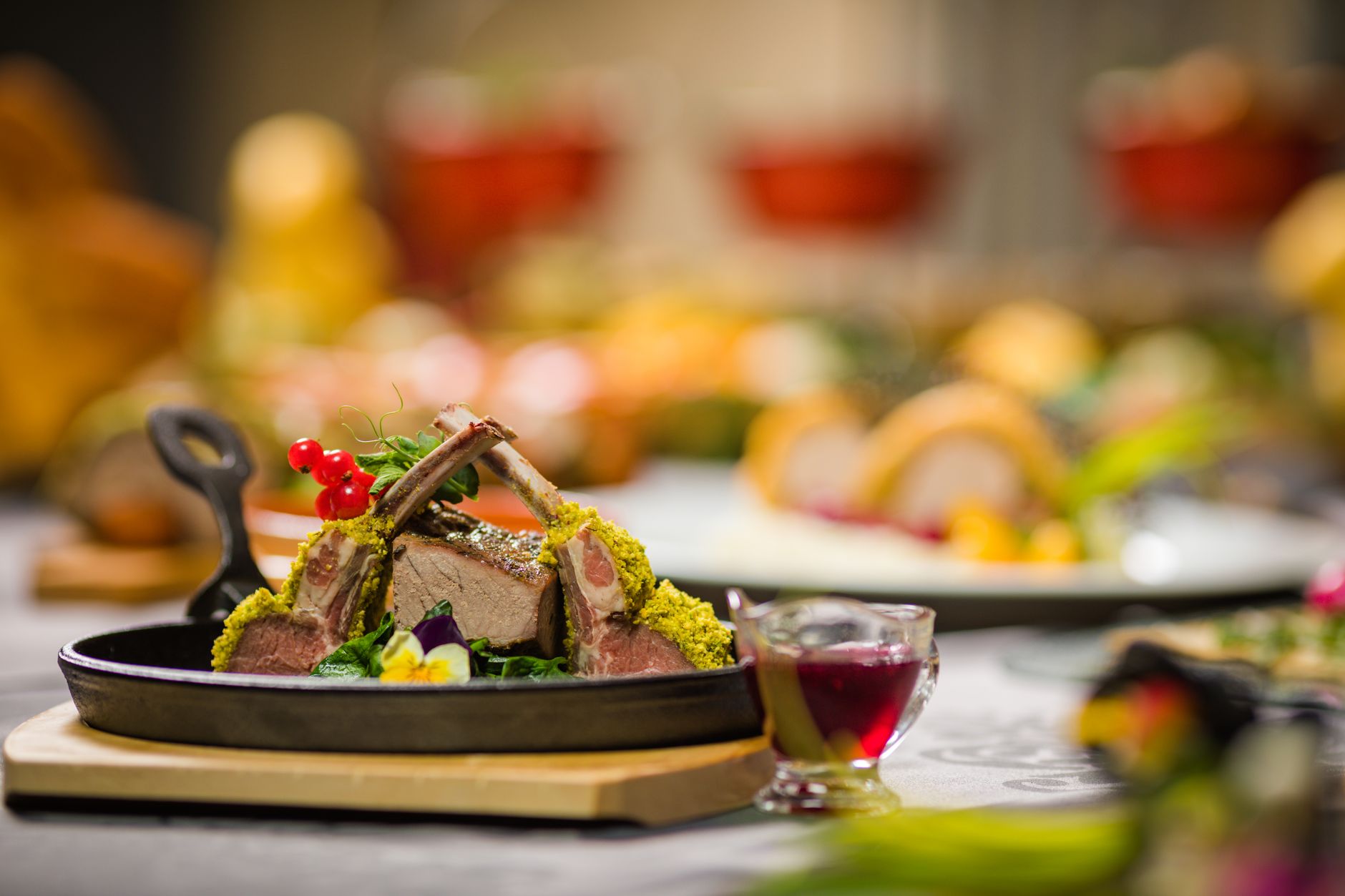 Close-up of a gourmet lamb rack with herbs, served with sauce, on a rustic table setting. Perfect for culinary themes.
