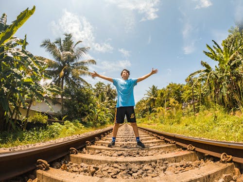 Boy in Blue Shirt Standing on Railway