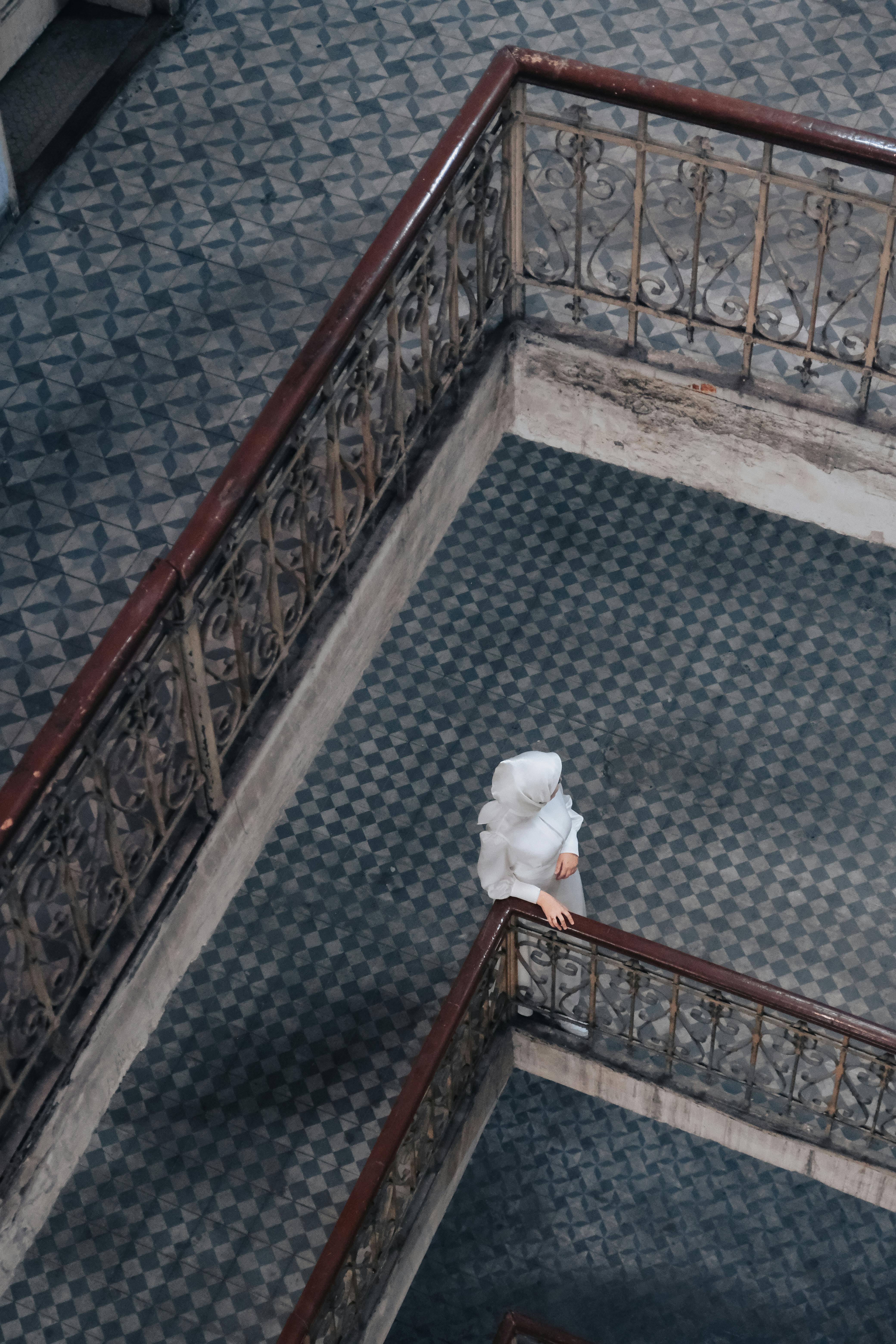 Aerial view of a woman in white coat standing on an artistic, urban staircase.