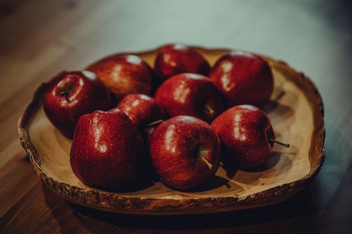 Free A close-up of fresh red apples in a rustic wooden bowl on a table. Stock Photo