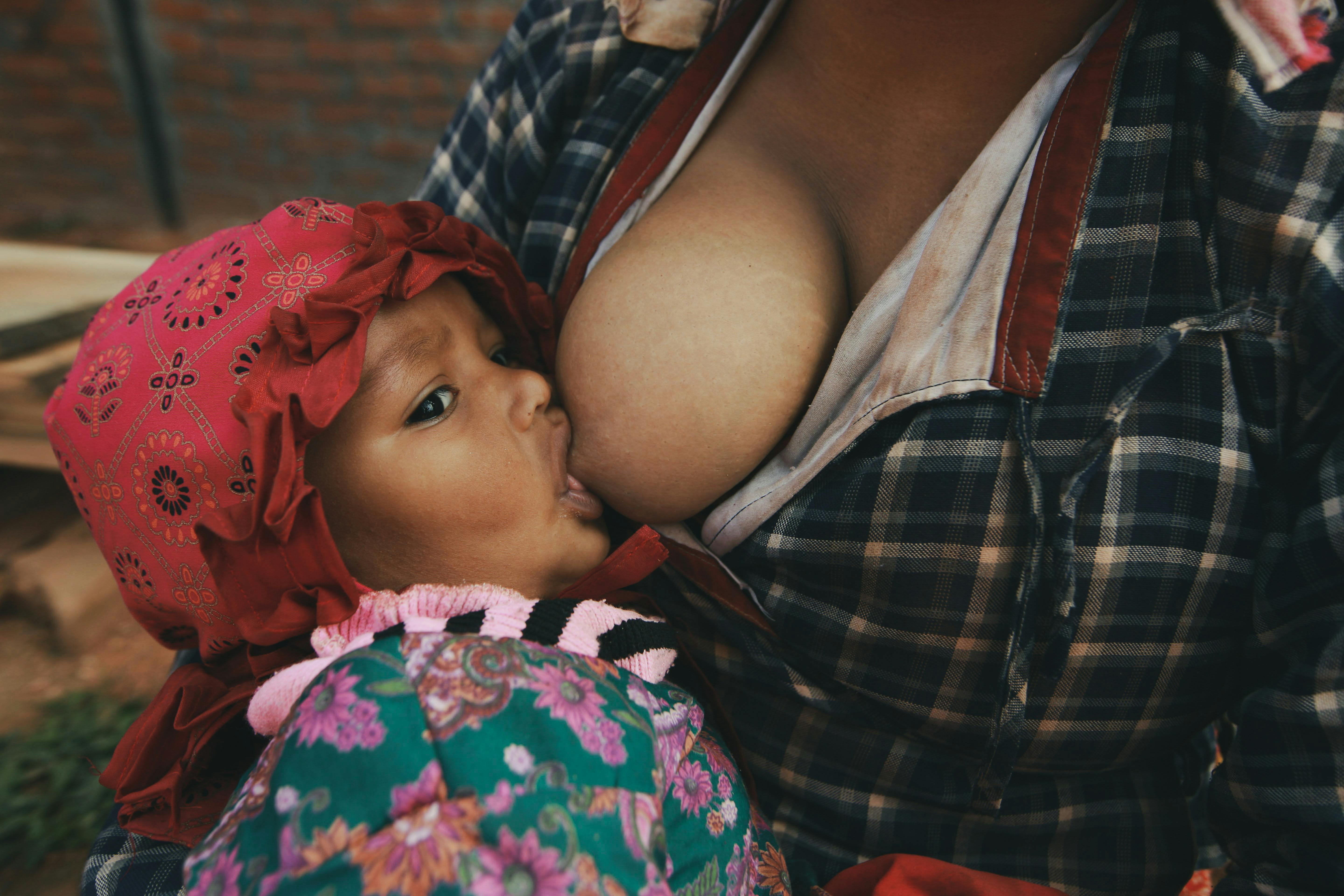 Mother breastfeeding baby outdoors, representing nurturing motherhood.