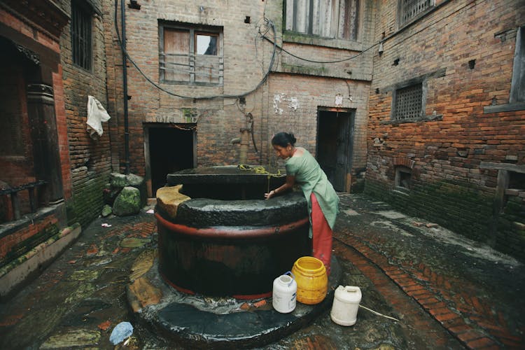 Woman With Buckets By Well 