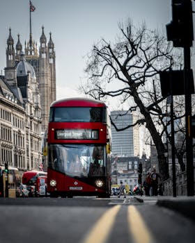 A classic red double-decker bus traveling on a busy street in London, England.