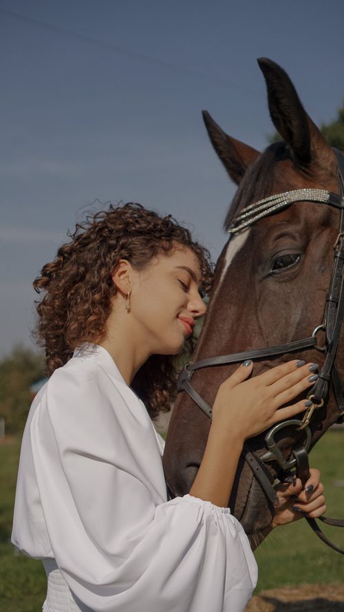 Free A woman in white embraces a horse, showcasing a serene connection outdoors. Stock Photo