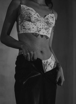 Elegant black and white photo of a woman in lace lingerie, showcasing tattoos.