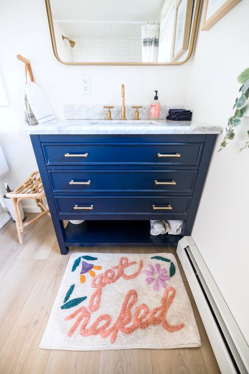 Free Elegant bathroom with chic vanity and a playful 'get naked' rug, perfect for modern interiors. Stock Photo