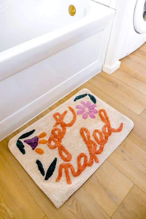 Free Bathroom rug with 'get naked' text in vibrant colors adds a fun touch. Stock Photo