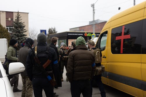 People Carrying Weapons Standing Near Parked Yellow Van