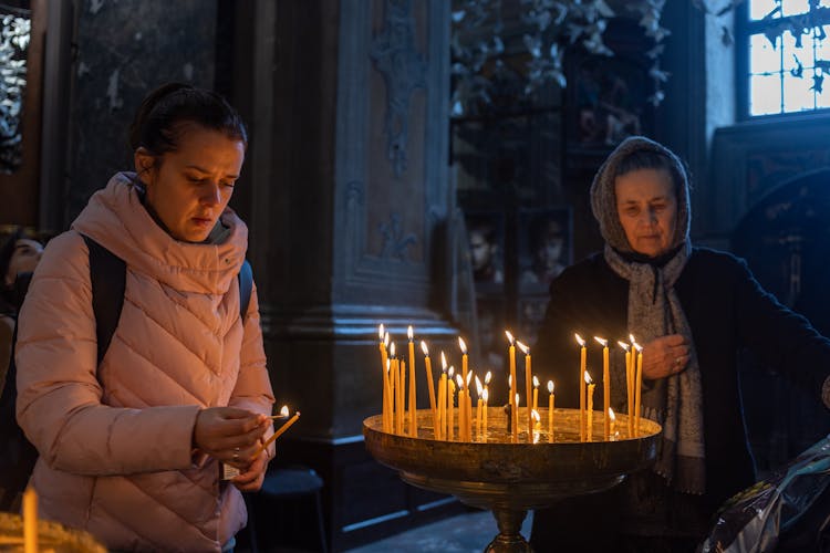 Women Offering Lighted Candles Inside A Church