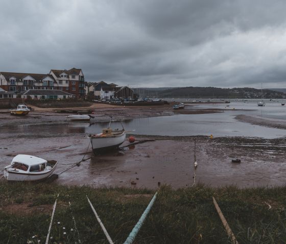 Small boats resting on the shore at low tide — photo by Ellie Burgin on Pexels