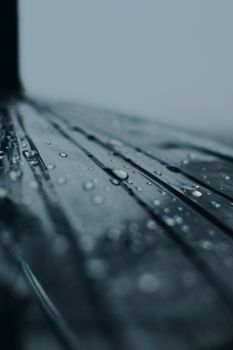 A detailed macro shot capturing water droplets on a reflective surface with a moody tone.