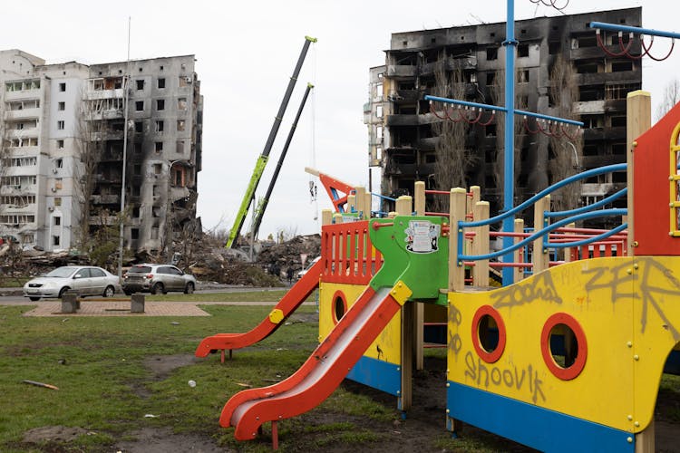 

A Playground With Burnt Buildings At The Background